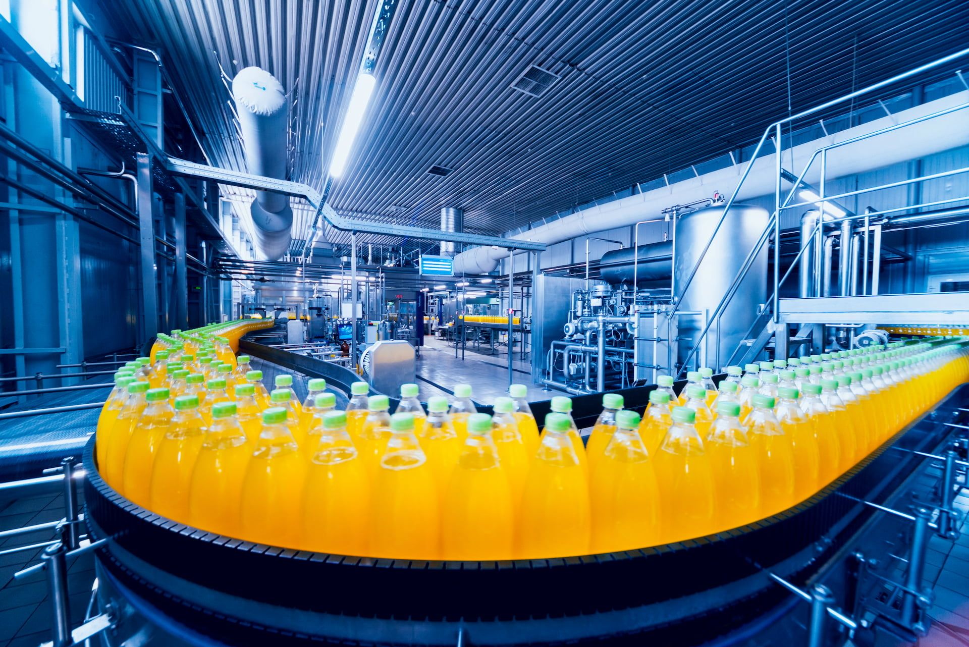 Fließband in einer Fabrik mit vielen Plastikflaschen gefüllt mit orangefarbener Flüssigkeit